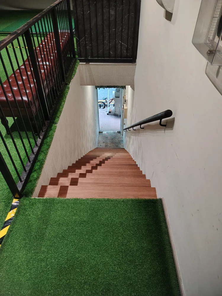 Staircase down from AnyBirdie to the street entrance, turf landing and leather bench