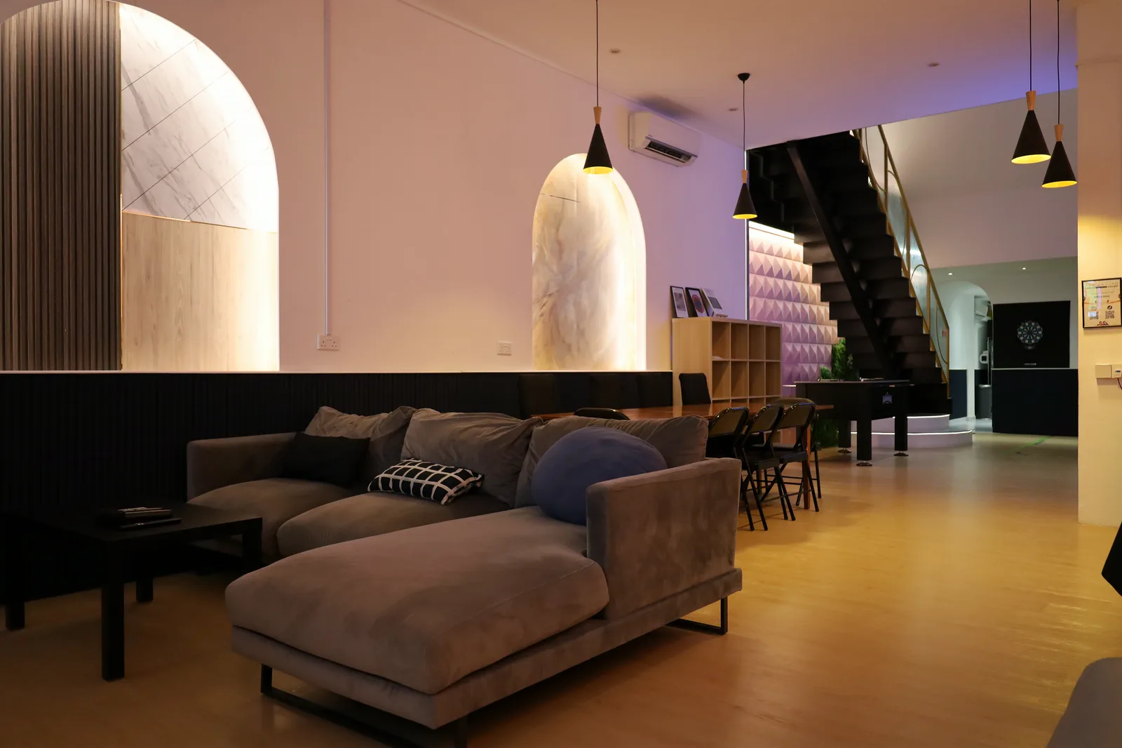 The Loft main hall with sectional sofa, arched alcoves and the staircase beyond